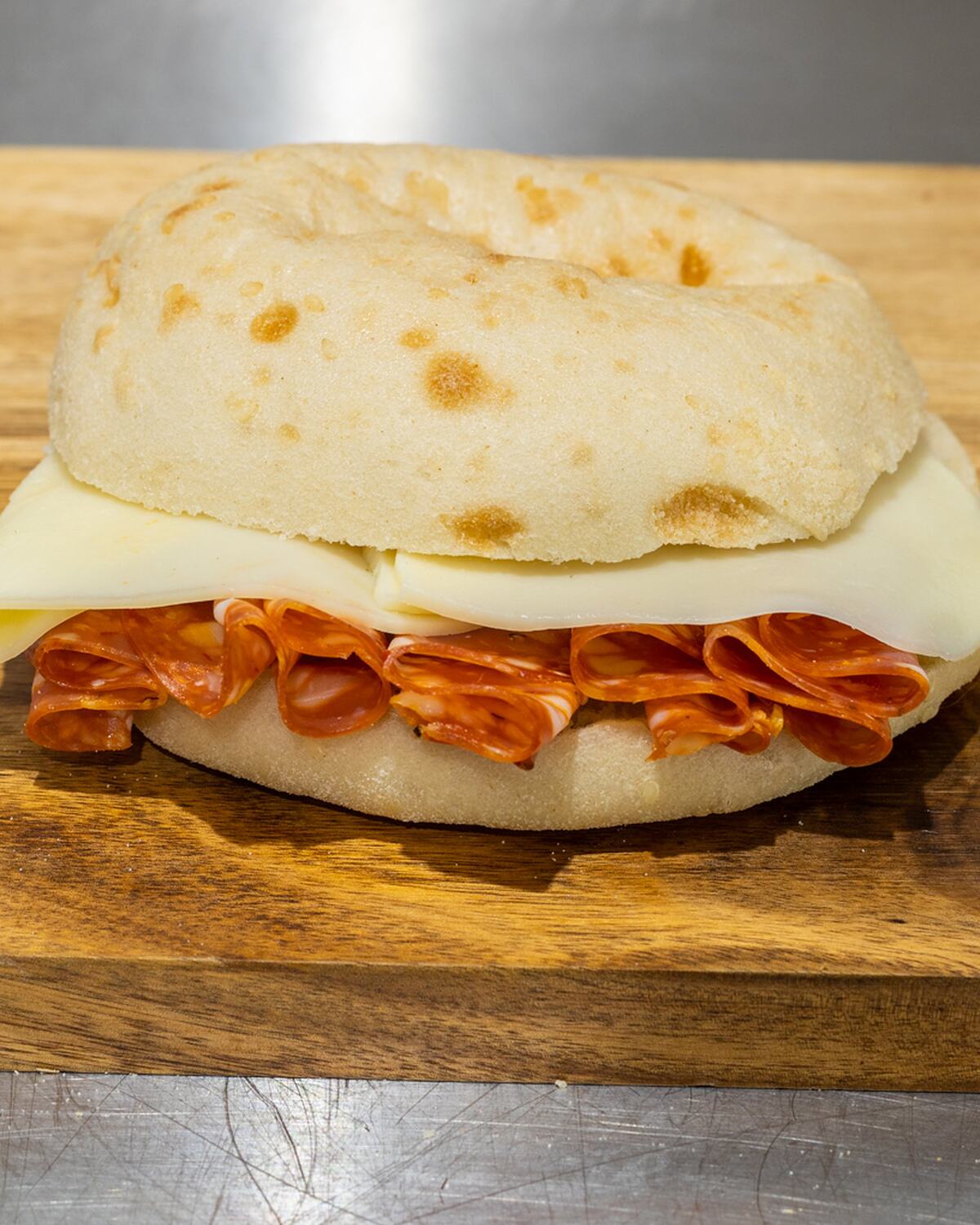 A Rose's Deli hot salami and provolone roll on the wooden counter